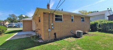 View of property exterior with a lawn, a chimney, brick siding, and a patio