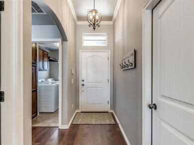 Doorway featuring dark wood-type flooring, a notable chandelier, separate washer and dryer, and ornamental molding