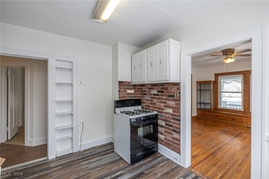Kitchen with white cabinets, black gas range, dark wood-style floors, a ceiling fan, and light countertops