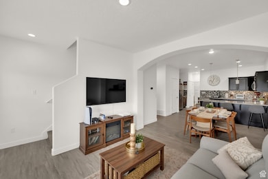 Living room with arched walkways, recessed lighting, light wood-style floors, and stairway