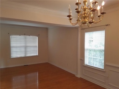 Spare room with a chandelier, wood finished floors, and crown molding