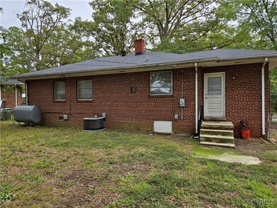 Back of property with cooling unit and a yard
