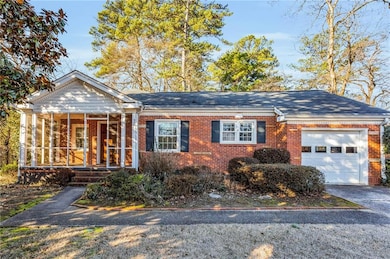 Ranch-style home featuring brick siding, a garage, a sunroom, and concrete driveway