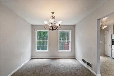 Empty room featuring a chandelier, baseboards, vis