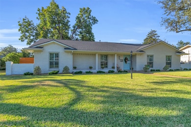View of front of home with a porch, roof with shingles, and brick siding