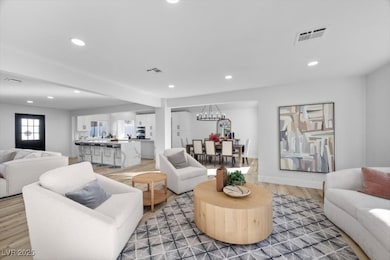 Living room with light wood-style flooring, recessed lighting, and a chandelier
