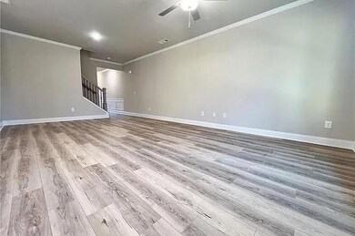 Unfurnished living room with wood finished floors, stairway, ornamental molding, and ceiling fan
