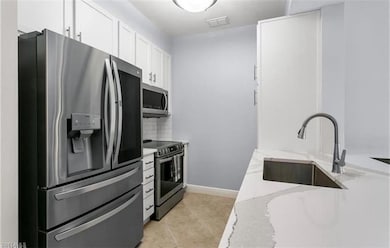 Kitchen with light stone counters, white cabinets,