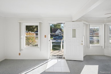 Doorway to outside featuring carpet, beam ceiling, and ceiling fan