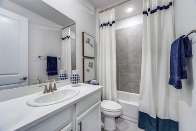 Full bath with shower / bath combo with shower curtain, vanity, light tile patterned floors, and a textured wall