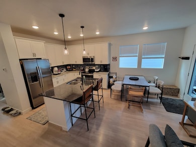 Kitchen with dark stone counters, stainless steel appliances, decorative backsplash, a breakfast bar area, and an island with sink