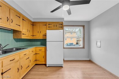 Kitchen with sink, tasteful backsplash, baseboard heating, white refrigerator, and light hardwood / wood-style floors