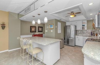 Kitchen with a tray ceiling, open shelves, white cabinets, tasteful backsplash, and appliances with stainless steel finishes