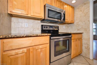 Kitchen featuring stainless steel appliances, stone countertops, light tile patterned flooring, tile walls, and recessed lighting