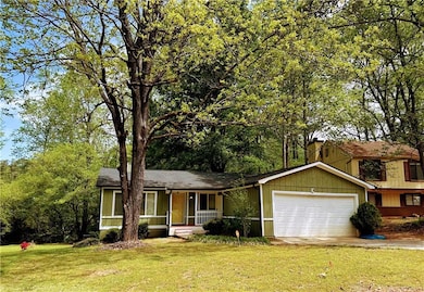 View of front of property with covered porch, a garage, a front yard, and concrete driveway