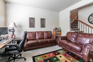 Carpeted living room featuring a desk and stairway