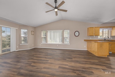 Unfurnished living room featuring dark wood-style floors, lofted ceiling, and a ceiling fan