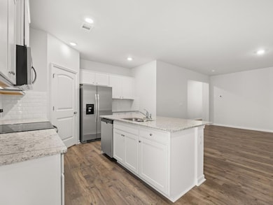 Kitchen with white cabinets, dark wood-style flooring, an island with sink, decorative backsplash, and recessed lighting