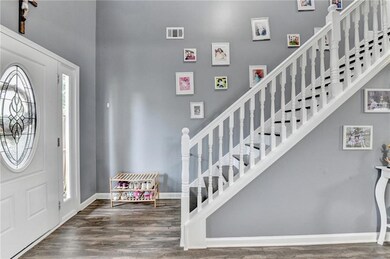 Entryway with a towering ceiling, wood finished floors, and stairway