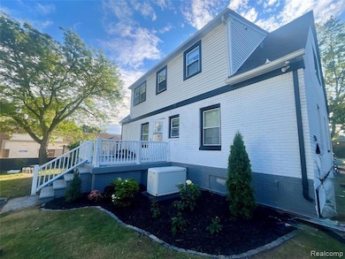 Rear view of property featuring a deck, brick siding, a yard, and stairway