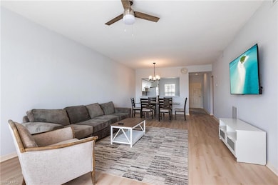 Living area featuring light wood-type flooring, ceiling fan, and a chandelier