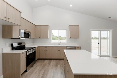 Kitchen featuring appliances with stainless steel finishes, light brown cabinets, light wood-style flooring, modern cabinets, and high vaulted ceiling