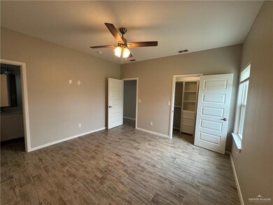 Unfurnished bedroom featuring baseboards, wood finished floors, a walk in closet, and a closet