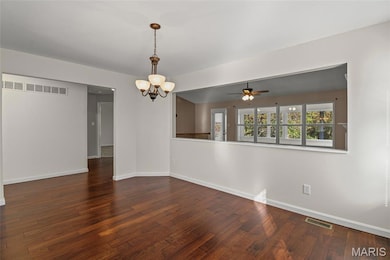 Empty room with a chandelier, ceiling fan, and dark wood-style floors