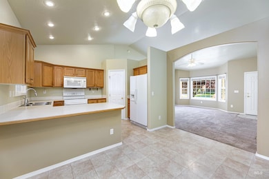Kitchen featuring white appliances, ceiling fan, light carpet, light countertops, and a peninsula