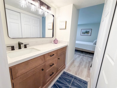Bathroom with vanity, light wood-style floors, and a textured ceiling