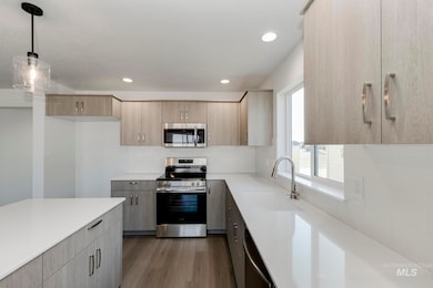 Kitchen with stainless steel appliances, dark wood-type flooring, hanging light fixtures, modern cabinets, and recessed lighting