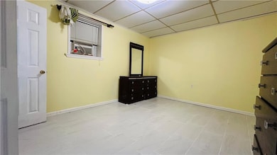 Unfurnished bedroom featuring baseboards and a drop ceiling