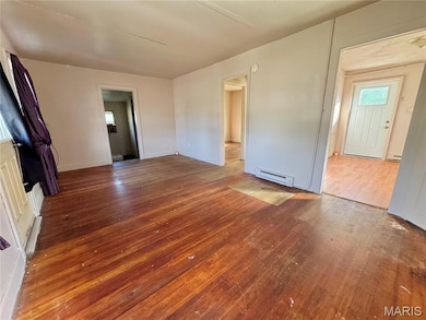 Unfurnished living room with wood-type flooring and a baseboard heating unit