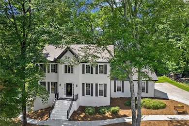 Colonial inspired home featuring a shingled roof and stucco siding