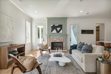 Living room featuring light hardwood / wood-style floors, crown molding, and a brick fireplace