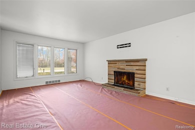Unfurnished living room featuring baseboards and a warm lit fireplace