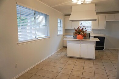 Kitchen featuring white cabinetry, island range ho