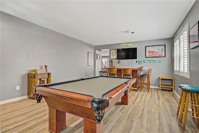 Recreation room featuring healthy amount of natural light, a dry bar, and wood finished floors