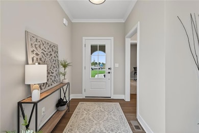 Doorway to outside with ornamental molding and wood finished floors
