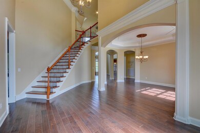 Stepping inside the foyer, you'll find hand-scraped wide-plank hardwood flooring, a 20-foot ceiling, staircase with wrought-iron spindles, new paint, and refined architectural molding details.