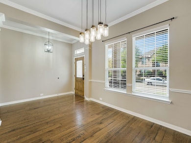 Entrance foyer with ornamental molding, hardwood / wood-style flooring, and a chandelier
