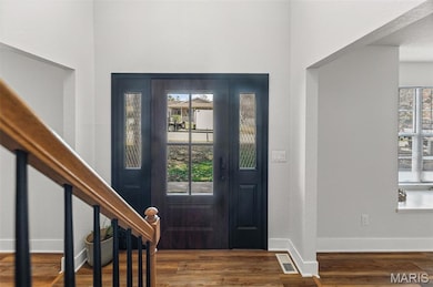 Entryway with dark wood-style floors and stairs