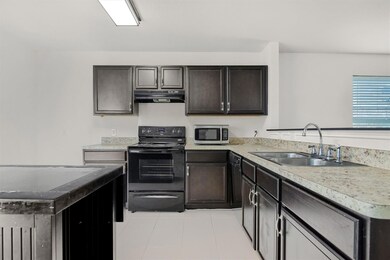 Kitchen with kitchen peninsula, black / electric stove, dark brown cabinetry, sink, and light tile floors