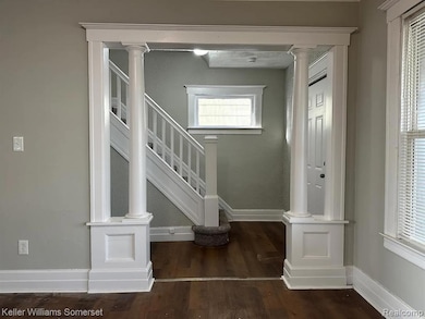 Stairs featuring wood finished floors and ornate columns
