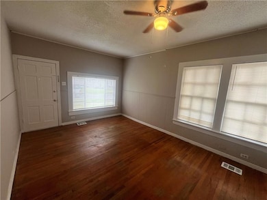 Unfurnished room featuring wood finished floors, a textured ceiling, baseboards, and a ceiling fan