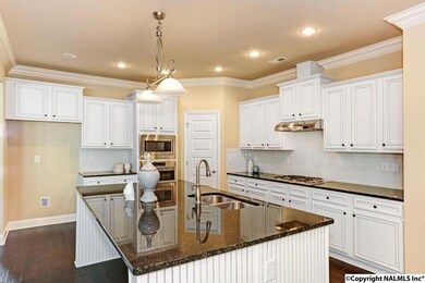 Gourmet kitchen!  Oversized island, natural gas cooktop, wall mount oven and microwave, granite countertops, tile backsplash, and beautiful lighting.