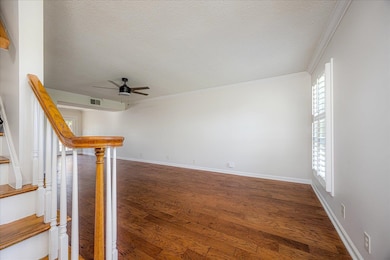 Unfurnished room featuring dark wood-type flooring, ornamental molding, a textured ceiling, and ceiling fan