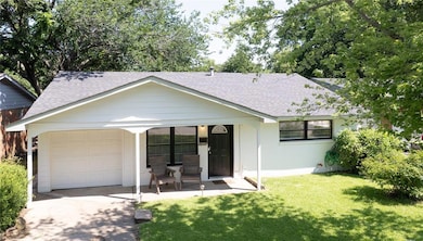 View of front of property featuring a shingled roof, a porch, a front yard, a garage, and concrete driveway