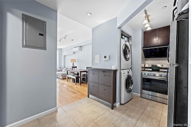 Kitchen featuring track lighting, appliances with stainless steel finishes, stacked washer / dryer, electric panel, and dark brown cabinets