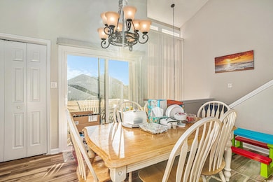 Dining area with wood finished floors, a chandelier, vaulted ceiling, and a textured wall